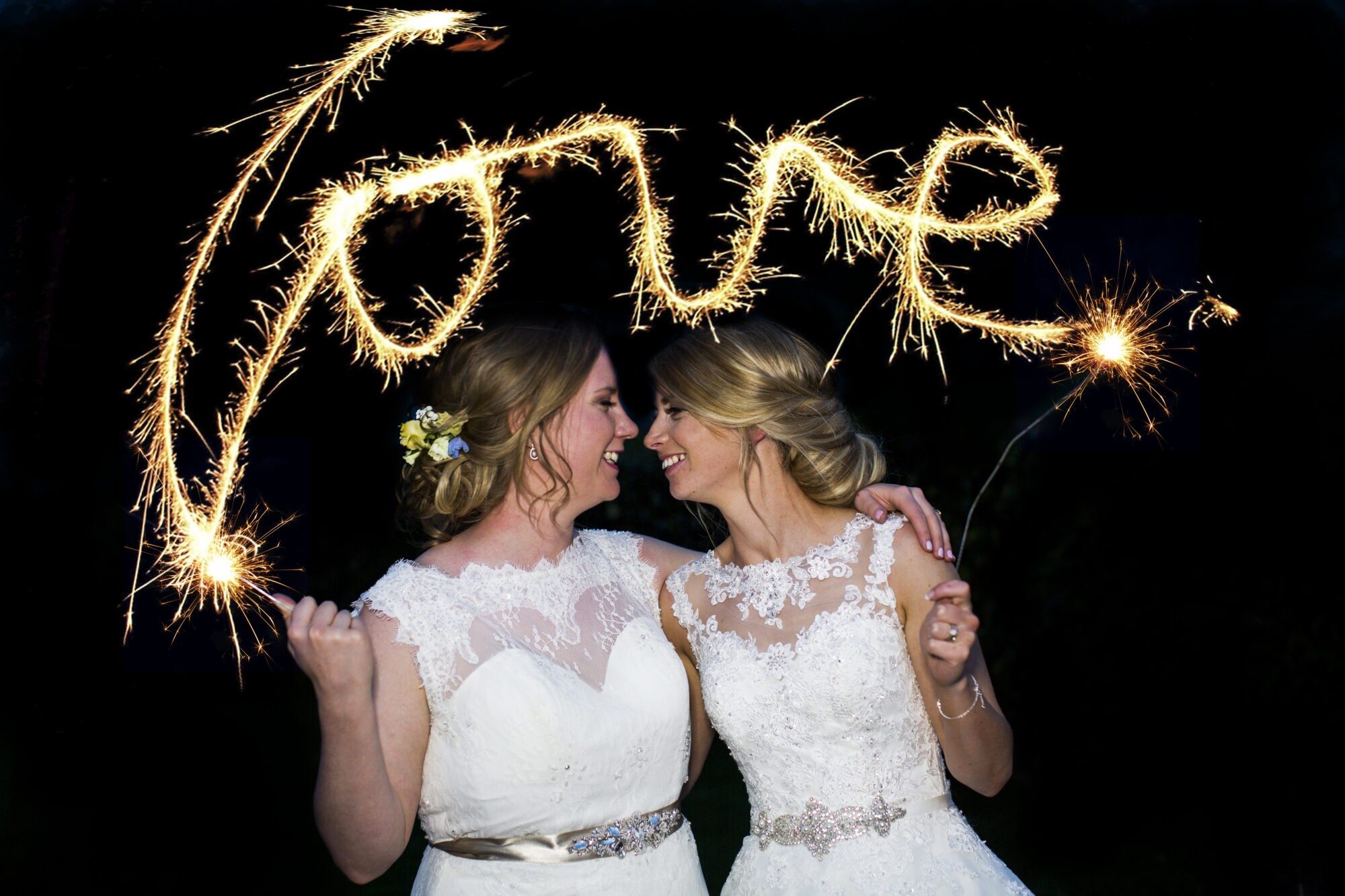 Happy couple at their wedding with sparklers spelling out 'love'